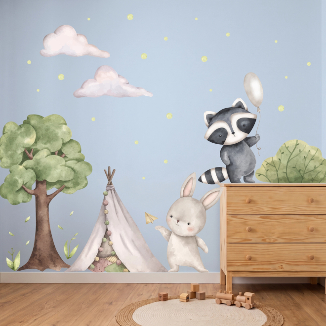 Adesivi murali con procione, coniglietto, albero e tenda indiana in stile acquerello applicati in una cameretta per bambini.