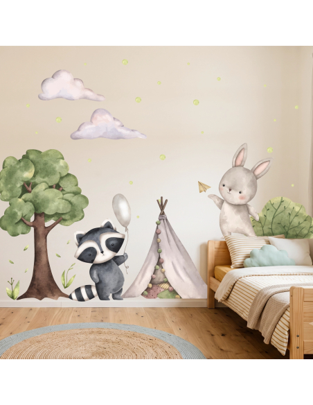Adesivi murali con procione, coniglietto, albero e tenda indiana in stile acquerello applicati in una cameretta per bambini.
